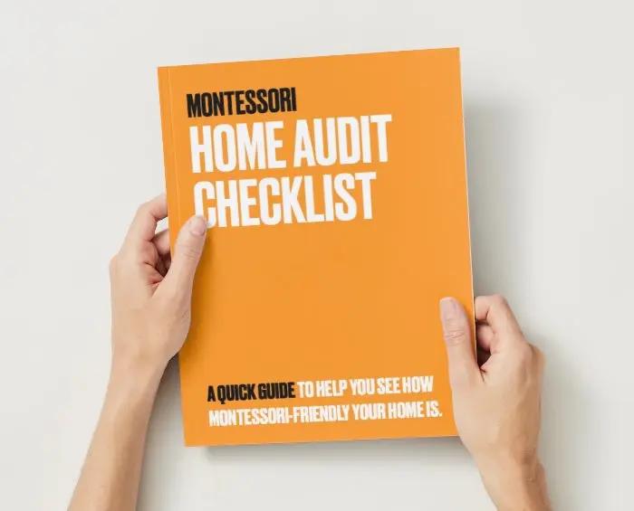 Orange book titled 'Montessori Home Audit Checklist' held by hands on a light background